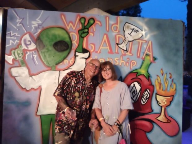 A couple smiling in front of a sign that says "World Margarita Championship."
