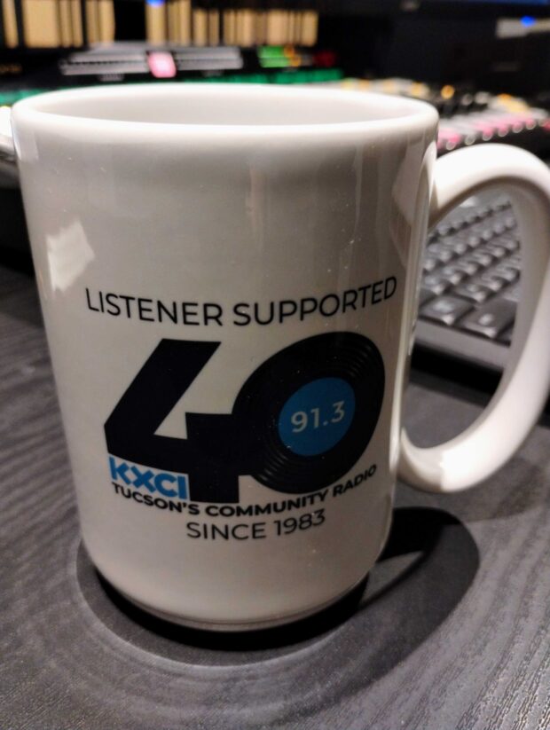 A white 15 ounce mug with KXCI's 40th Anniversary Logo on the front and back.
