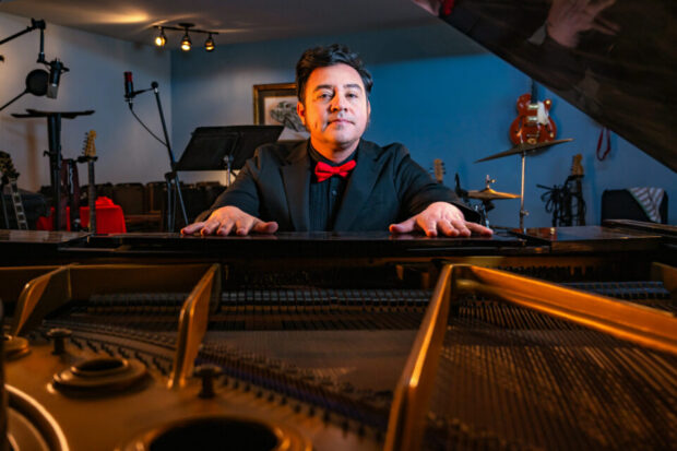 Sergio Mendoza sits behind an open baby grand piano
